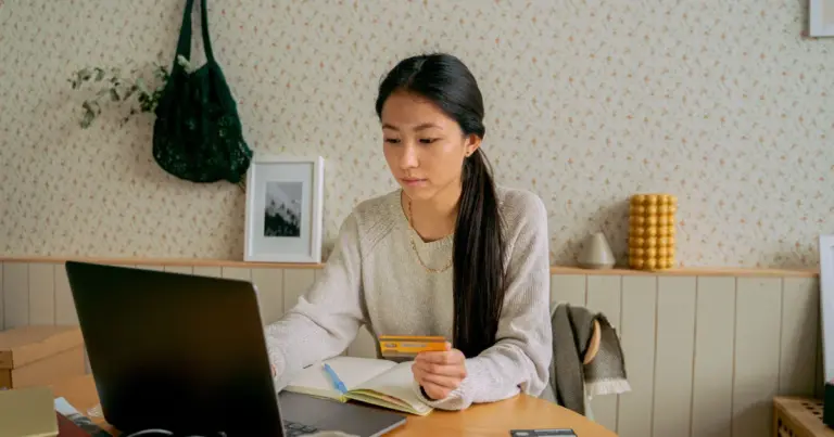 Donna che tiene una carta e usa il laptop a casa