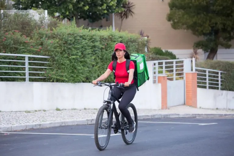 Rider in bicicletta che consegna cibo in un quartiere cittadino