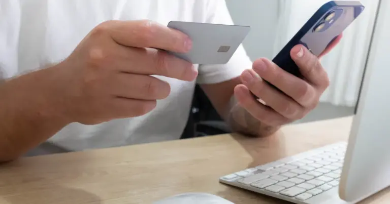Persona che tiene una carta prepagata e uno smartphone