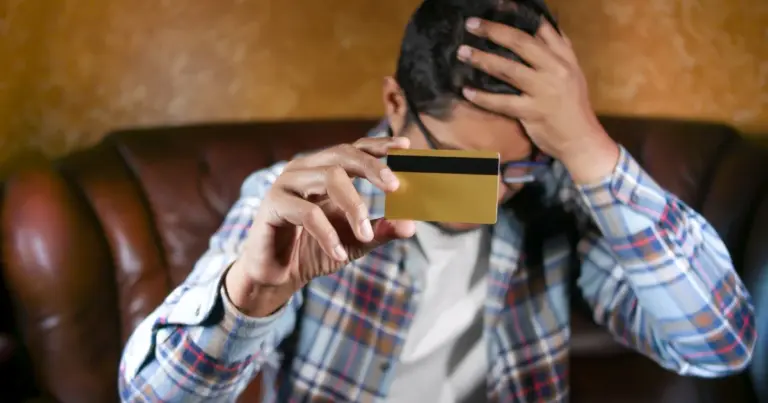 Uomo pensieroso che tiene in mano una carta di credito a casa