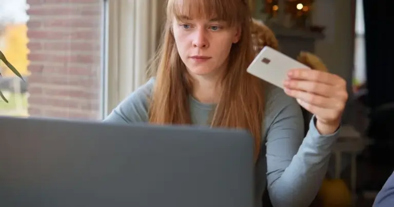 Donna che guarda una carta di credito davanti al computer