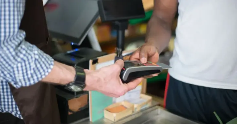 Cliente che paga la spesa con carta contactless alla cassa del supermercato