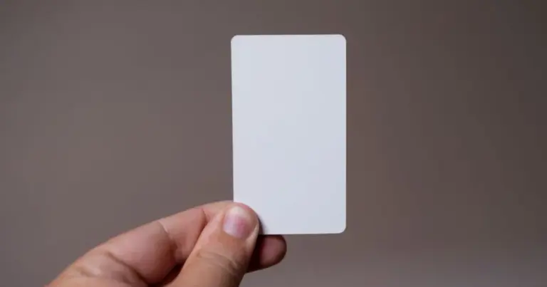 Mano che tiene una carta fedeltà bianca prima di pagare la spesa