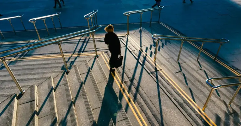 Persona che scende una scalinata soleggiata in città