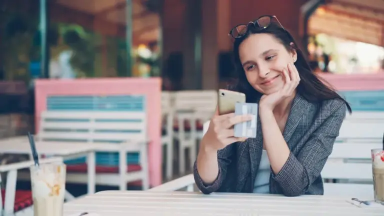 Donna che guarda il telefono con una carta in mano
