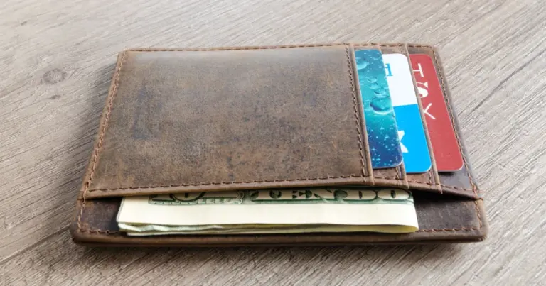 Portafoglio in pelle con contanti e carte su un tavolo di legno